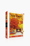 A 1000-piece puzzle by New York Puzzle Company with a linen-style finish, featuring a classic The New Yorker cover of a covered bridge, autumn foliage, and a school bus.