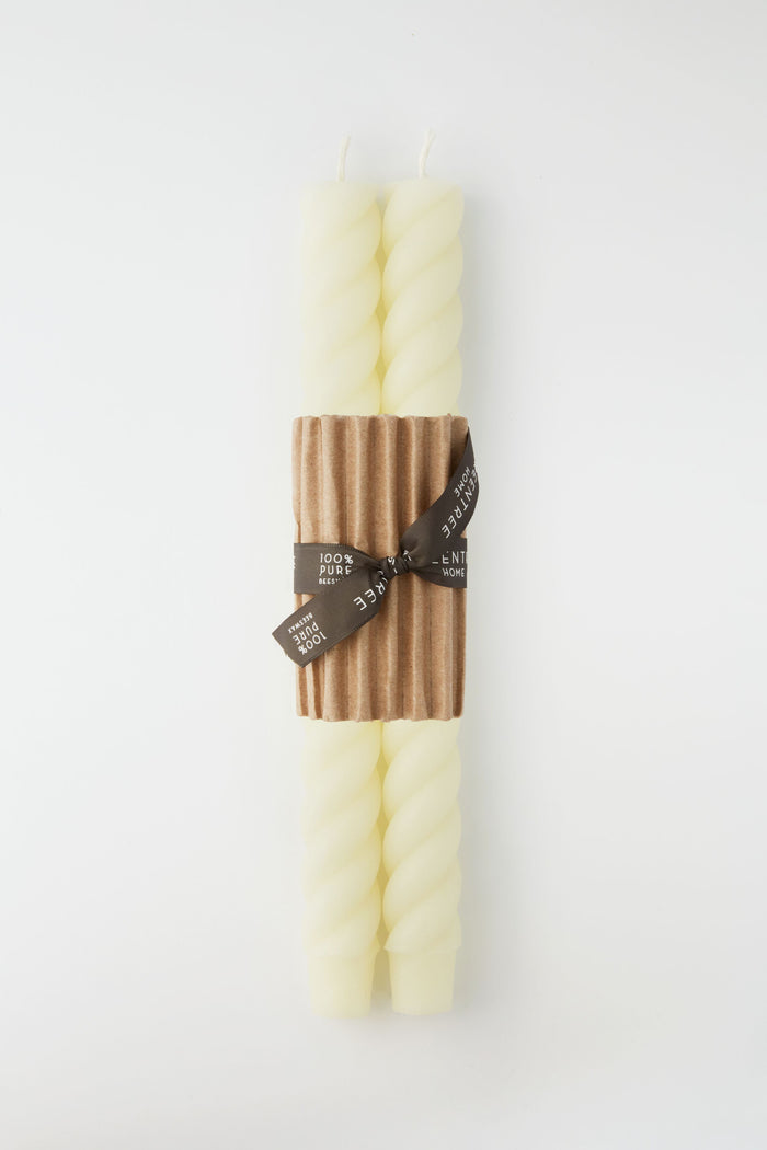 Two ivory spiral taper candles by Greentree Home are bundled with a brown corrugated band and tied with a black ribbon—beautiful hand-poured candles that make a thoughtful housewarming gift.