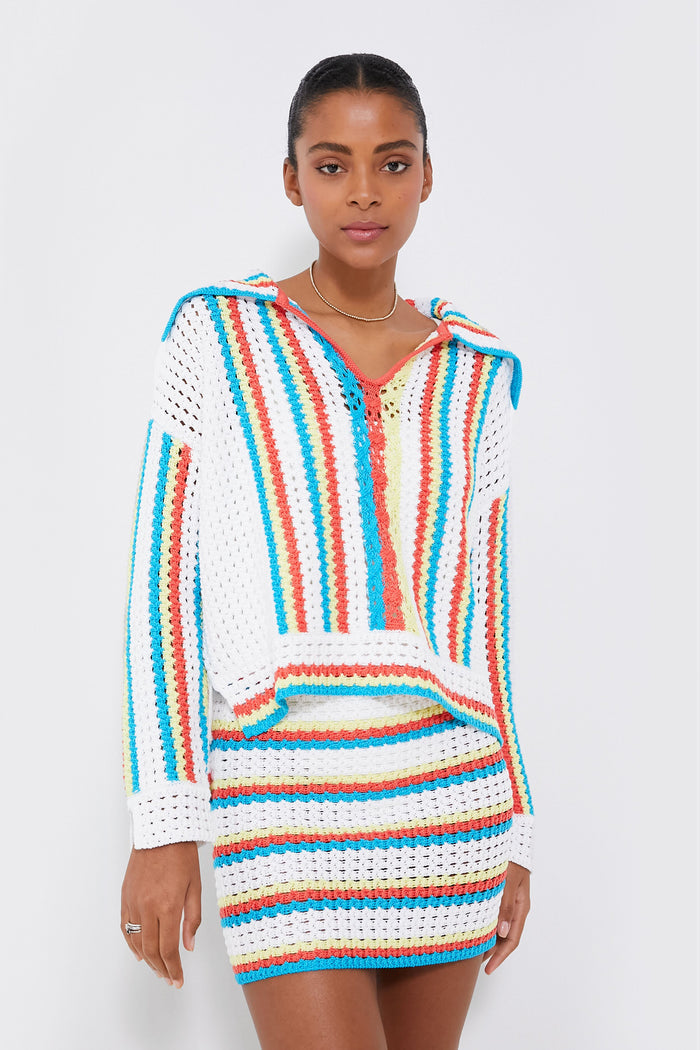 A woman wears a Solid & Striped hooded crocheted pullover and matching skirt with colorful white, blue, orange, and yellow stripes, crafted from soft mercerized cotton.