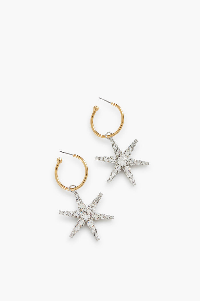 A pair of gold hoop earrings with silver, rhinestone-encrusted star pendants—luxury accessories handmade in New York by Jennifer Behr.