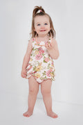 A little girl wears an Angel Dear classic ruffle romper with a floral design.