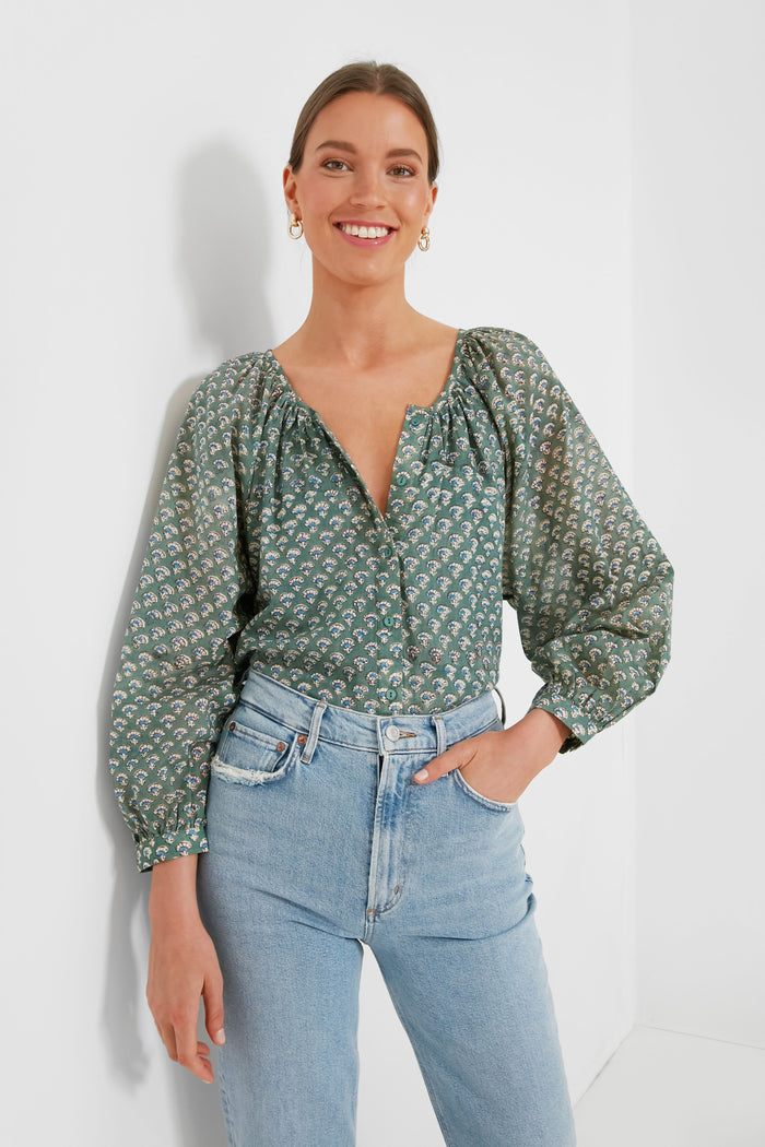 A woman smiles in a green hand-block printed blouse with balloon sleeves from Love Tomas by Emerson Fry, paired with light blue high-waisted jeans.