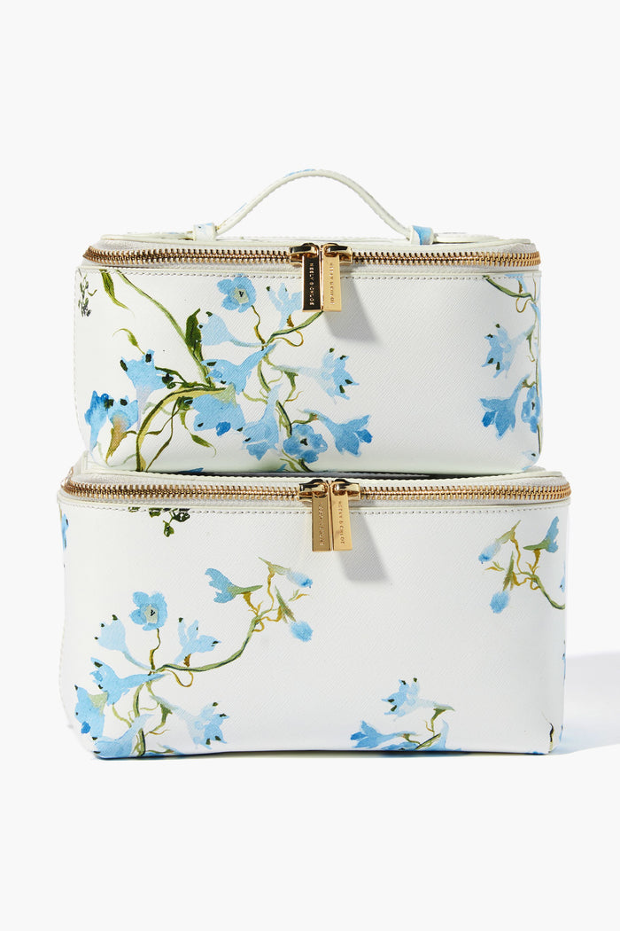 Two white rectangular Neely & Chloe x Inslee zippered toiletry bags with gold hardware and blue floral prints, stacked neatly. A chic holiday gift, these stylish bags offer elegance and smart organization for travel or your vanity.