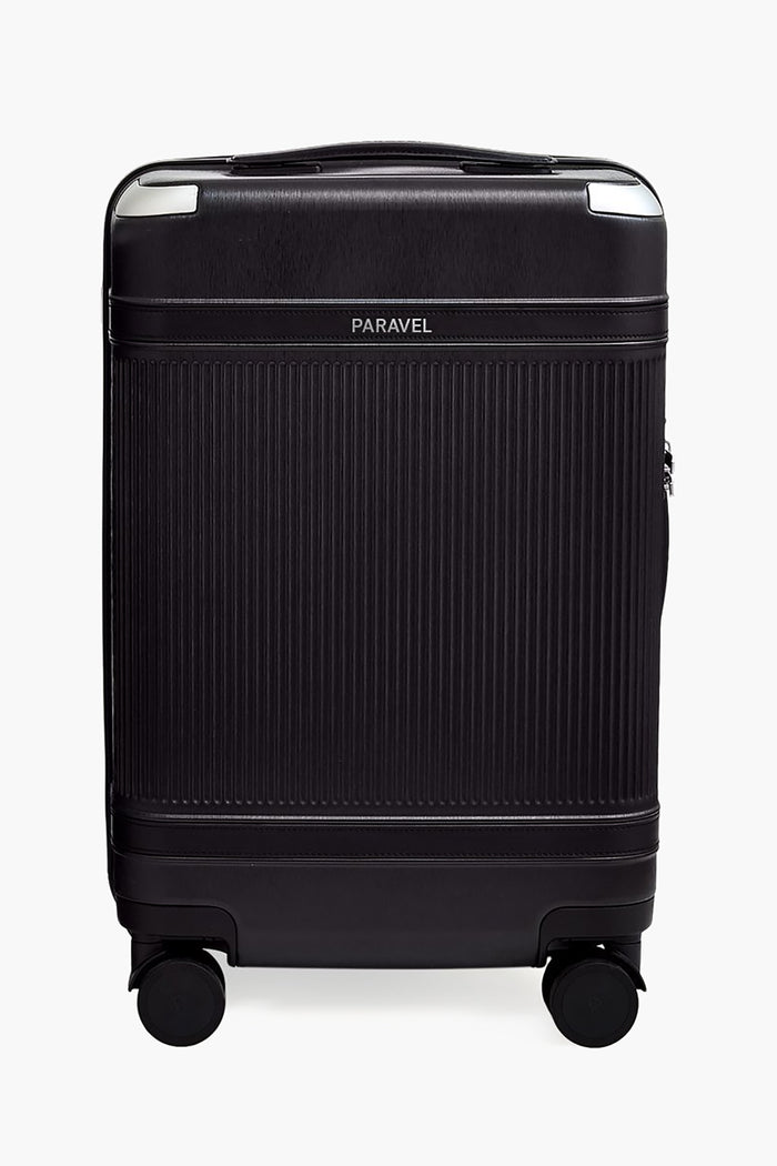 The Paravel black sustainable carry-on features a ribbed hard-shell made from recycled polycarbonate, silver accents, and four wheels. The Paravel logo is displayed near the top center.