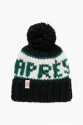 A black hand-knit merino wool beanie by Lele Sadoughi with a pom-pom, white and green stripes, and "APRES" in green across the front.