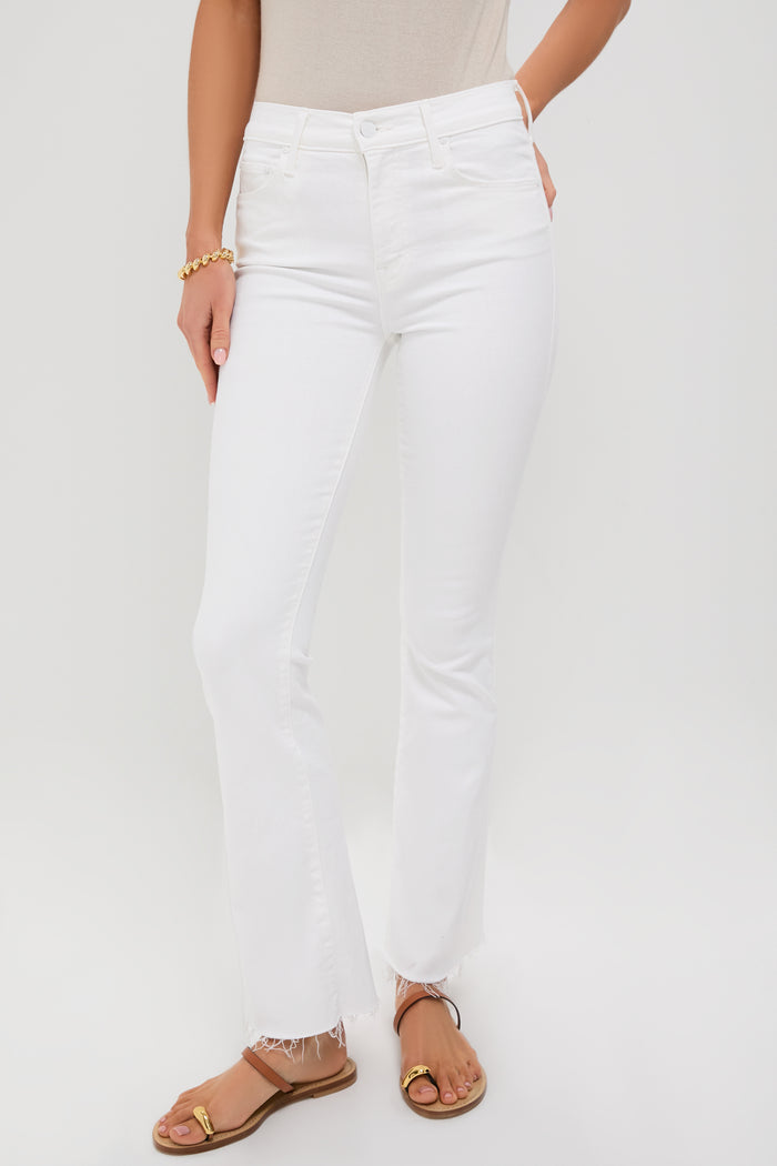 Wearing high-waisted, white MOTHER Weekender Fray jeans with frayed hems, a beige top, gold bracelet, and tan sandals for an effortlessly stylish look.