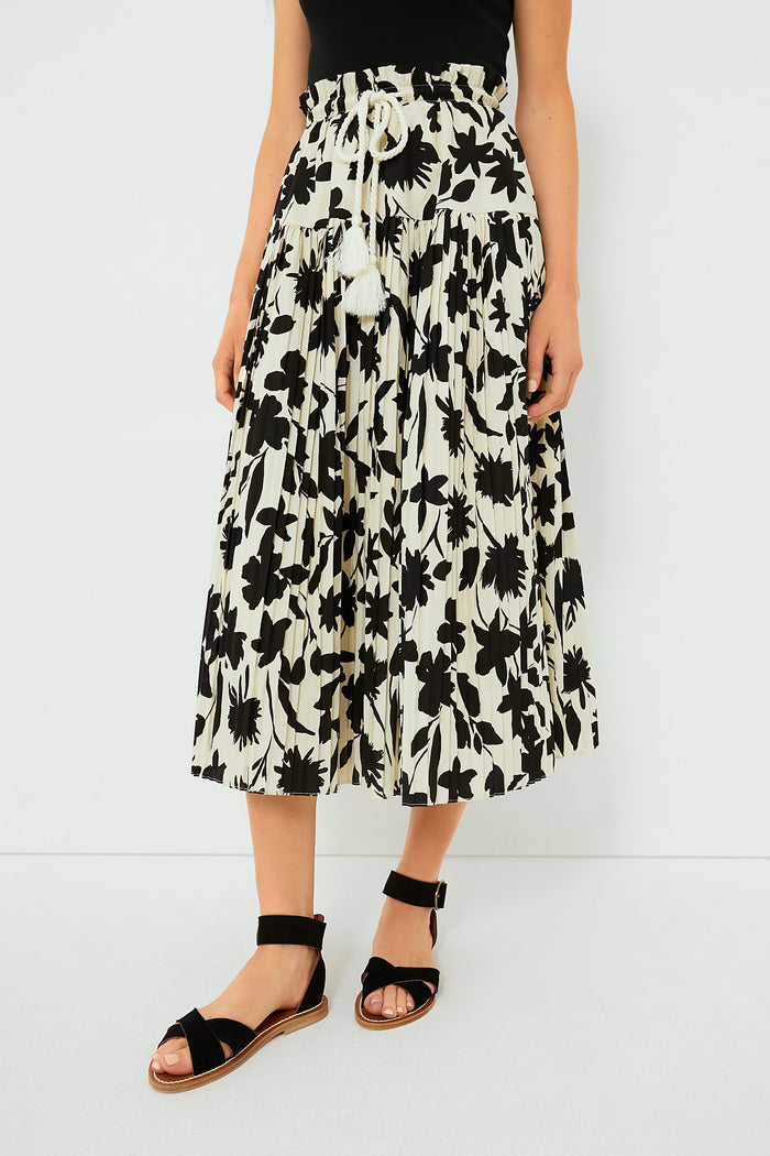 Someone wears a black top, a Moon River Ivory Floral Skirt with a rope belt and ruffled waistband, and black sandals.