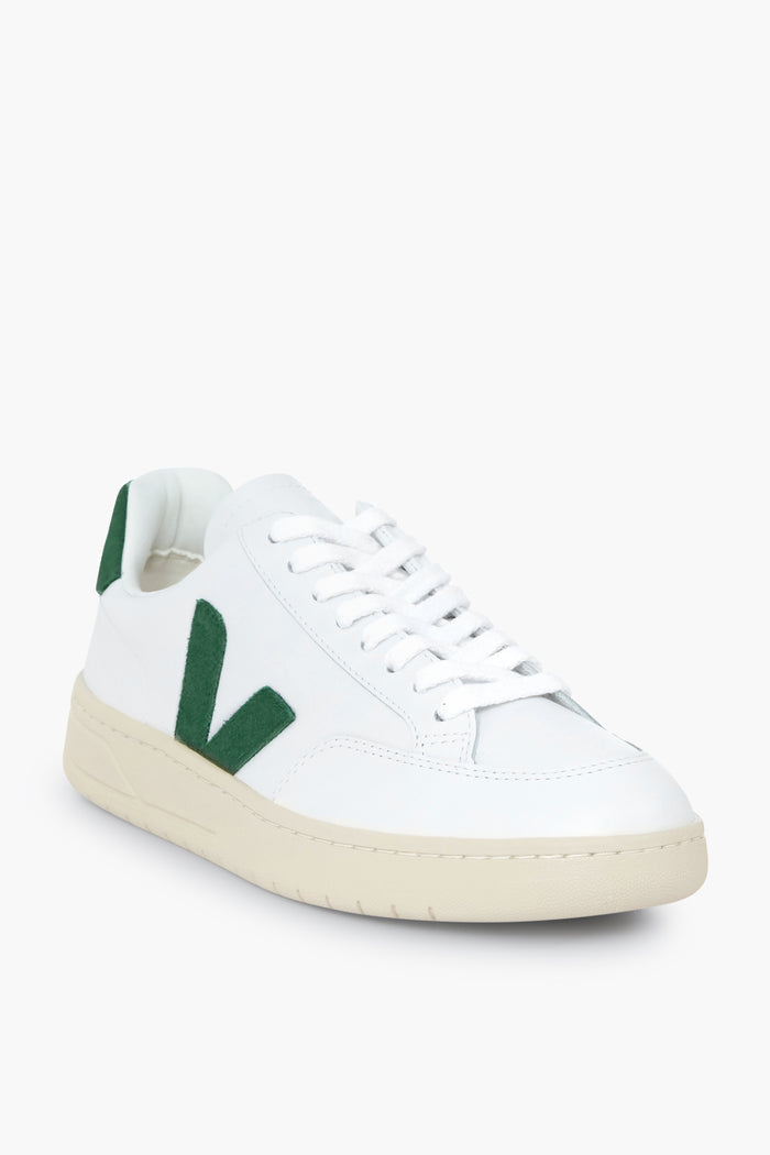 VEJA white sneakers featuring a green V logo on the side, white laces, and an off-white rubber sole, made from recycled materials.