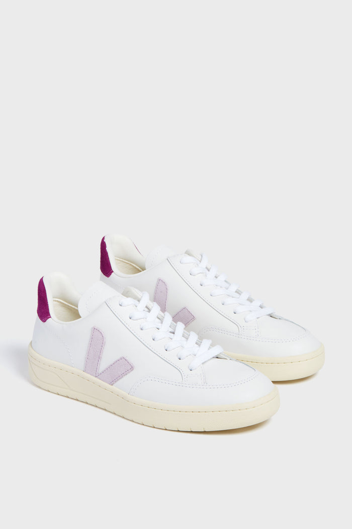A pair of white VEJA sneakers featuring light purple V logos and purple heel accents, made from recycled materials for eco-friendly style.
