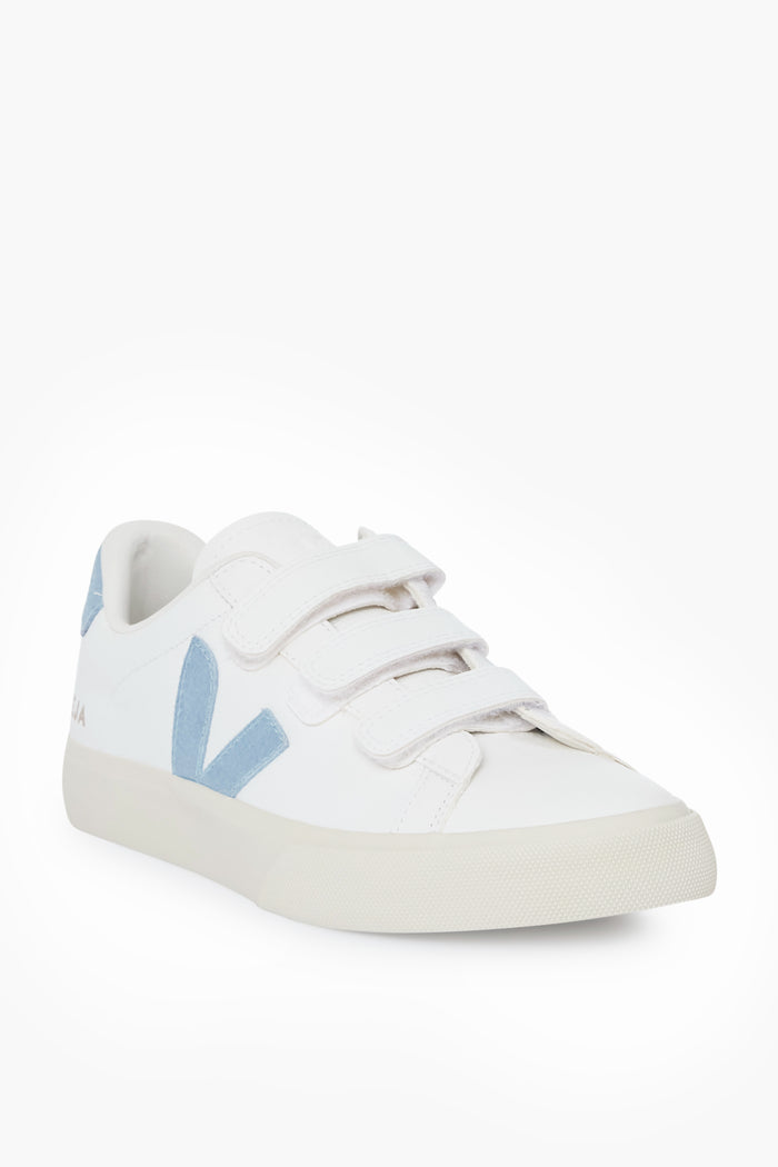 A white VEJA sneaker with two Velcro straps, light blue accents, and a side V logo, made from chrome free leather for eco-friendly style.
