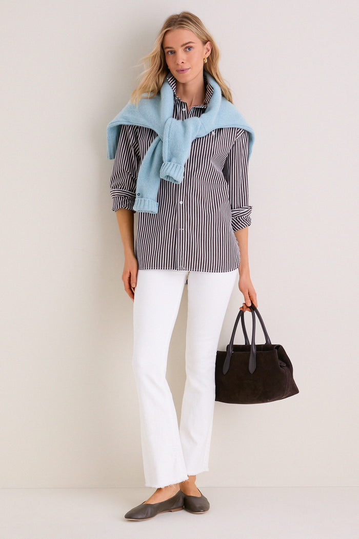 Model wearing classic Fairest Of Them All The Hustler Ankle Fray jeans; high-rise, kick flare, effortlessly styled with a knit sweater and tote, embodying high-end, fun sophistication.