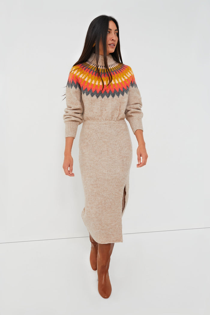 A woman wears a beige Saylor Fair Isle sweater dress featuring a colorful patterned yoke, long sleeves, ribbed turtleneck, and front slit, styled with brown knee-high boots.