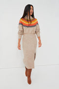 A woman wears a beige Saylor Fair Isle sweater dress featuring a colorful patterned yoke, long sleeves, ribbed turtleneck, and front slit, styled with brown knee-high boots.