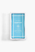 A white rectangular ceramic tray in chinoiserie style holds a blue package labeled "Hampton Guest Towel Tray" by Two's Company.