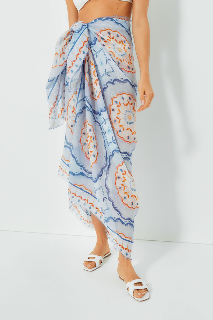 Wearing an ASHA x Tuckernuck blue and orange patterned pareo tied at the waist, paired with white sandals and a bare midriff.