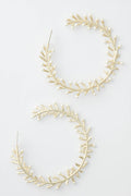 Nicola Bathie's large, circular gold hoop earrings are adorned with delicate pearls and leaf-shaped accents, creating a floral bud-inspired design.