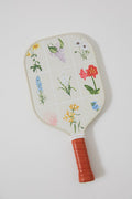 The Tnuck Sport x Recess Pickleball paddle features a red grip, a grid of colorful flowers on cream, and is made with fiberglass and a honeycomb core.