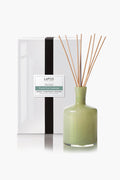 A green ceramic reed diffuser with sticks stands before a white LAFCO New York Fresh Cut Gardenia box, filling your space with elegant home fragrance and the fresh scent of gardenia.