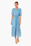 A woman wears a blue patterned maxi dress with puff sleeves and a tie waist from Love Tomas by Emerson Fry, made of organic cotton and hand block printed for the India Collection.