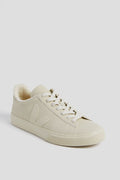The VEJA beige low-top sneaker features a lace-up front, textured sole, side logo, and a soft fleece-style inner lining, all crafted from sustainable materials.