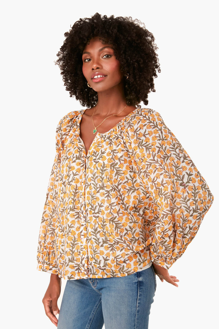 A woman wears the Love Tomas by Emerson Fry boho-chic floral button-up blouse with puffed long sleeves, paired with blue jeans.