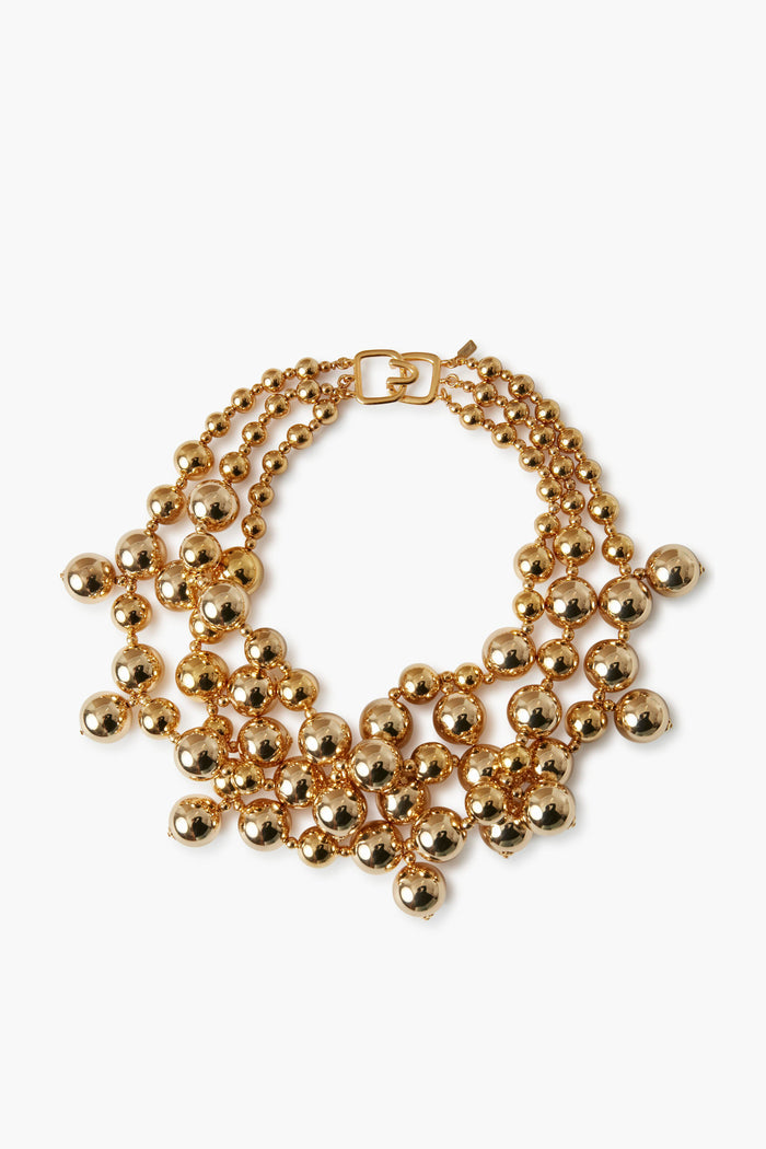 The Kenneth Jay Lane gold-plated beaded necklace features three rows of large, shiny, spherical beads and a rectangular clasp—an ideal statement piece for costume jewelry lovers.
