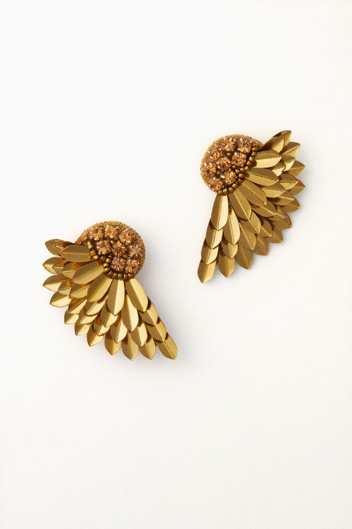 Deepa Gurnani’s gold wing earrings feature layered, feather-like metal pieces radiating from a beaded semicircular base—an eye-catching statement accessory.