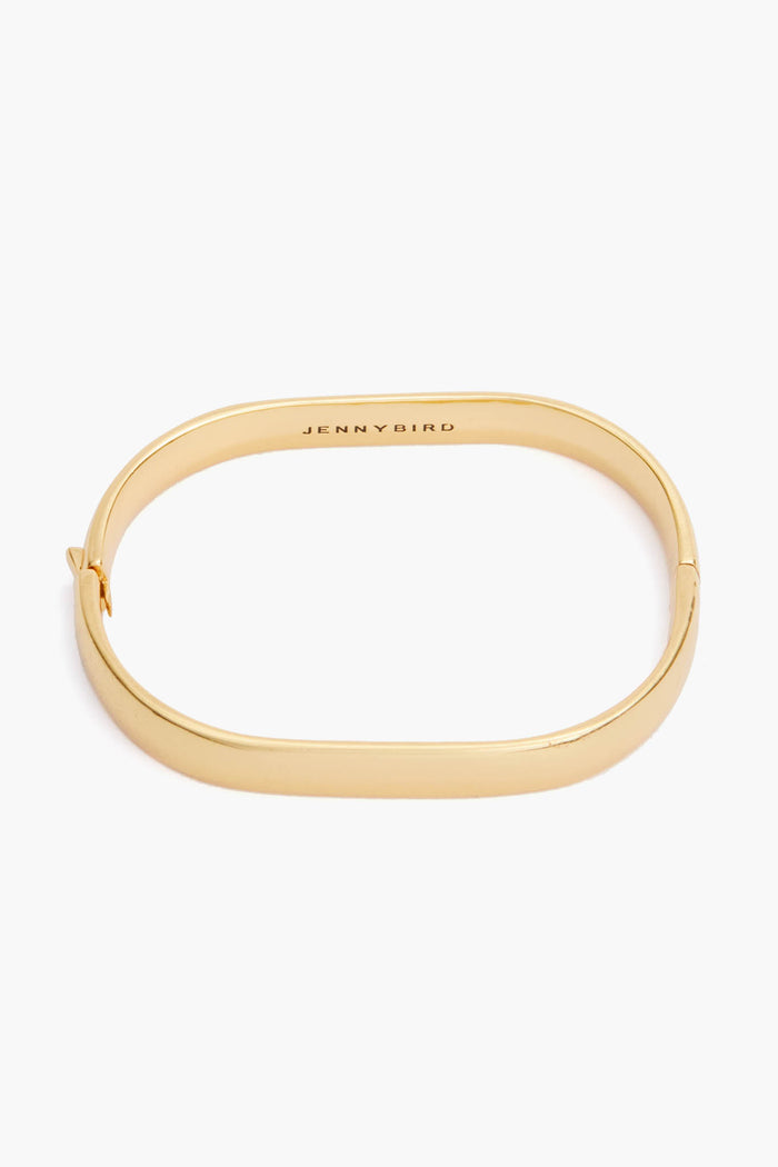 A vintage-inspired oval bangle from Jenny Bird, crafted from 14K gold-dipped brass with a smooth finish, hinged clasp, and "JENNY BIRD" engraved inside.