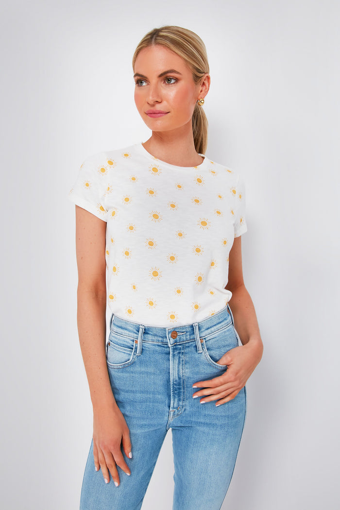 A woman wears a super-soft Marine Layer crew neck white t-shirt with yellow sun prints and light blue jeans.