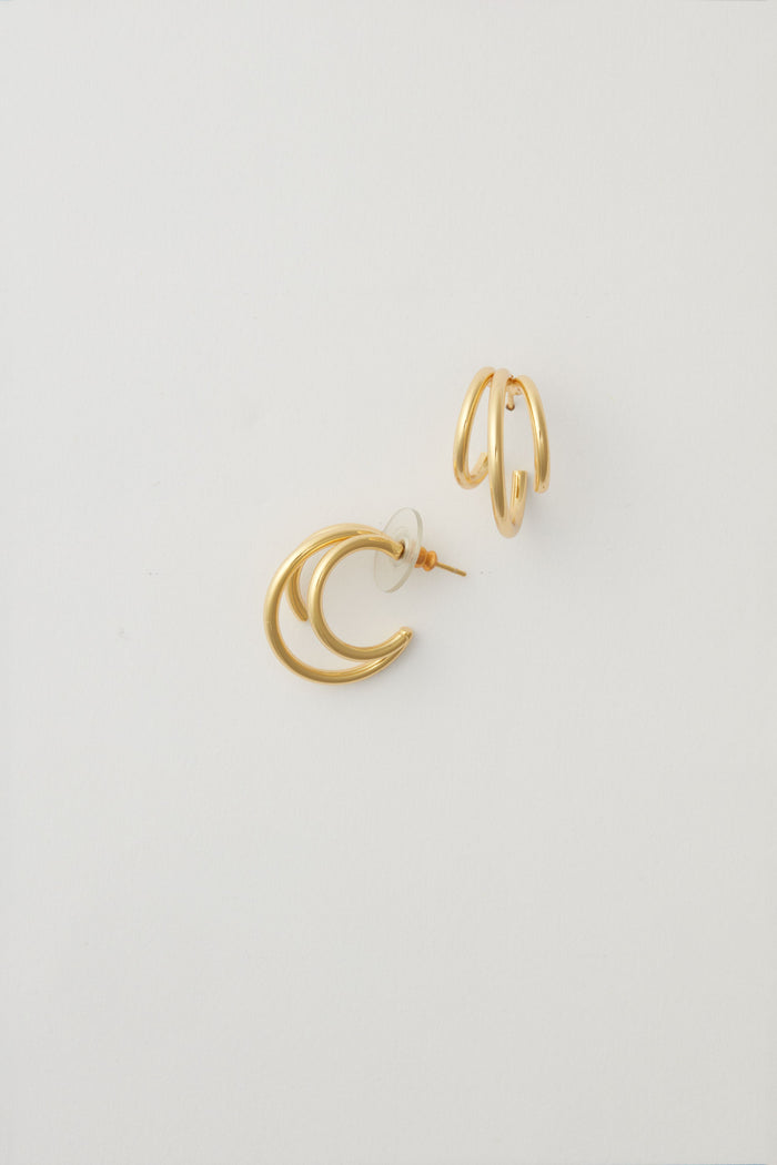 Two mismatched gold earrings from Alexa Leigh shine—one with overlapping crescent shapes, the other with two parallel 14k Gold Fill hoops—perfect for ear stacking or fans of our Triple Threat Earrings.