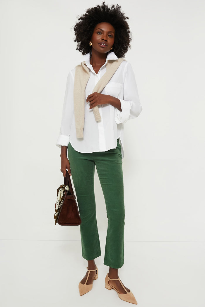 Woman models classic Green Corduroy Ashford Pants with effortless style, paired with a white shirt, beige sweater, and nude heels. A fun, high-end look.