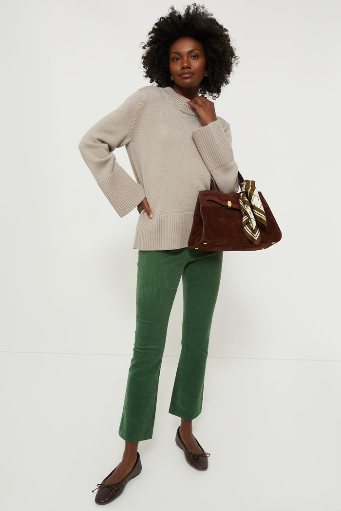 Black woman models classic Green Corduroy Ashford Pants with a cozy knit sweater, creating an effortless, high-end look. She accessorizes with ballet flats and a suede tote.