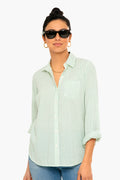 Woman wearing dark sunglasses, gold earrings, and a light green striped TROVATA Birds of Paradis Grace Classic Shirt with rolled-up sleeves.