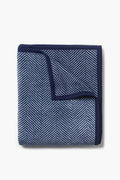 A machine-washable ChappyWrap blanket, neatly folded in a blue and navy herringbone pattern with a solid navy border.