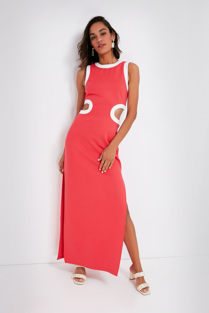 A woman poses gracefully in a retro-inspired look, wearing the STAUD sleeveless, floor-length coral maxi dress featuring white circular accents at the waist.