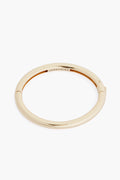 The Jenny Bird Gia Bangle is a simple, round 14K gold tone bracelet featuring a subtle engraved logo inside—perfect for adding elegance to your jewelry collection.