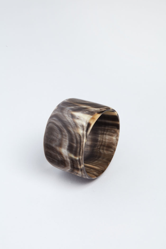Harkiss Designs presents a wide, smooth bangle bracelet crafted from Ankole cow horn, featuring a polished marbled brown and beige design—an elegant fair trade gift.