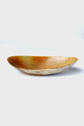 The Be Home oval-shaped, shallow horn bowl features a polished amber-toned surface and smooth texture. Handcrafted and ethically sourced, it's perfect for those who appreciate unique home goods.