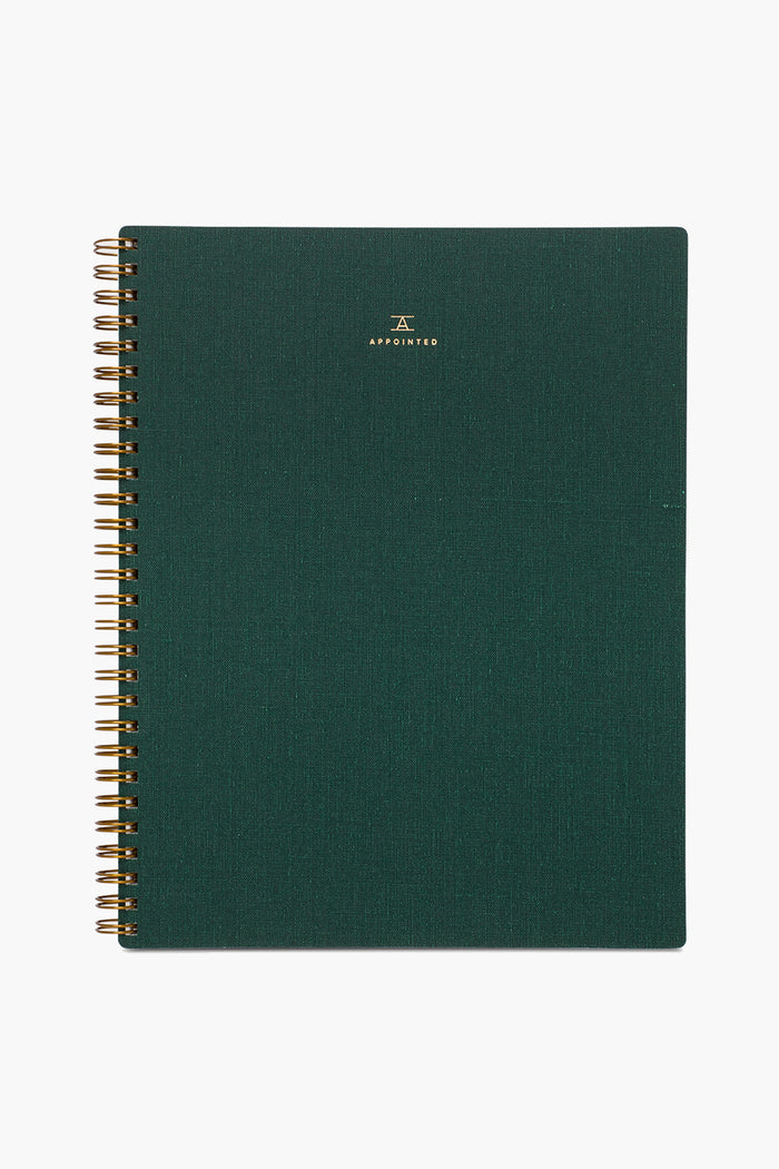 A spiral-bound APPOINTED Hunter Green Lined Notebook with a textured book-cloth cover, gold branding at the top, and made from recycled paper.