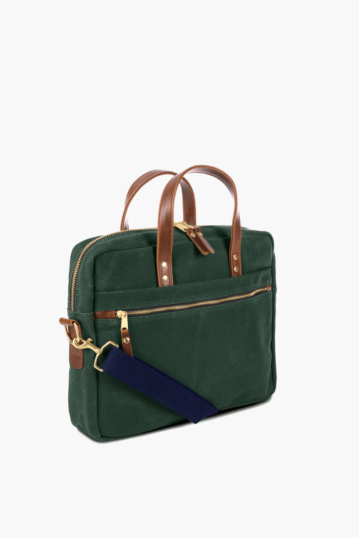 The Hudson Sutler Heritage Brief Case features green waxed cotton, brown leather handles, gold-tone zippers, and a detachable navy shoulder strap.