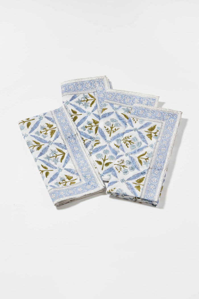 Three folded cotton napkins by Locust Walk feature a blue floral and geometric pattern, inspired by Hydrangea Blue Garden Trellis Napkins.