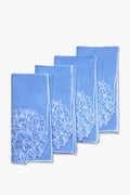 Four folded blue linen dinner napkins by Chefanie, featuring white floral embroidery, are arranged in a staggered stack—perfect for a coastal tablescape.
