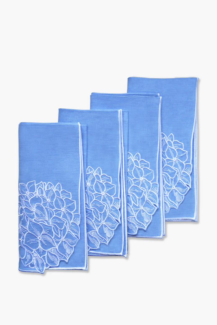 Four folded blue linen dinner napkins by Chefanie, featuring white floral embroidery, are arranged in a staggered stack—perfect for a coastal tablescape.
