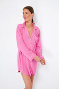 A woman smiles, looking to the side in a long-sleeved pink Eberjey TENCEL Modal pajama shirt with white piping and a chest pocket.