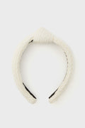 Lele Sadoughi white braided fabric headband featuring a top knot design, displayed in a minimalist setting.