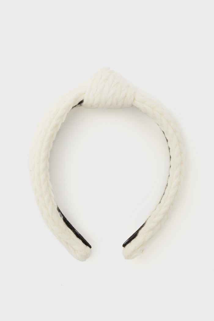 Lele Sadoughi white braided fabric headband featuring a top knot design, displayed in a minimalist setting.