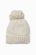 The Look by M hand-knit beanie features a soft cream color, a large pom-pom on top, and a cozy textured design.
