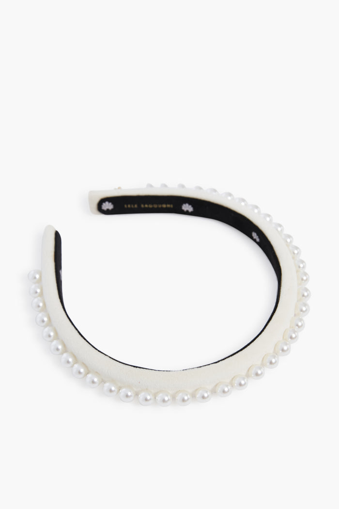 A Lele Sadoughi-inspired headband featuring a row of faux pearls, delicate floral accents, and a black inner lining.
