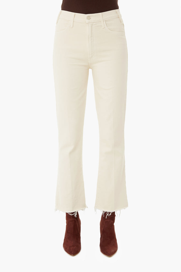 A person wearing MOTHER high-waisted, off-white cropped ankle jeans with raw hems and brown suede boots; upper body is partially visible.