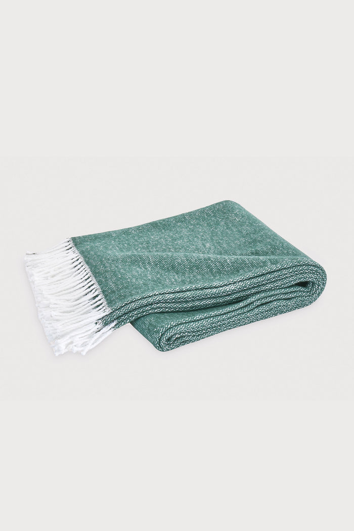 A folded Matouk Pezzo Throw in jade green cotton with a white fringe, shown on a plain light background.